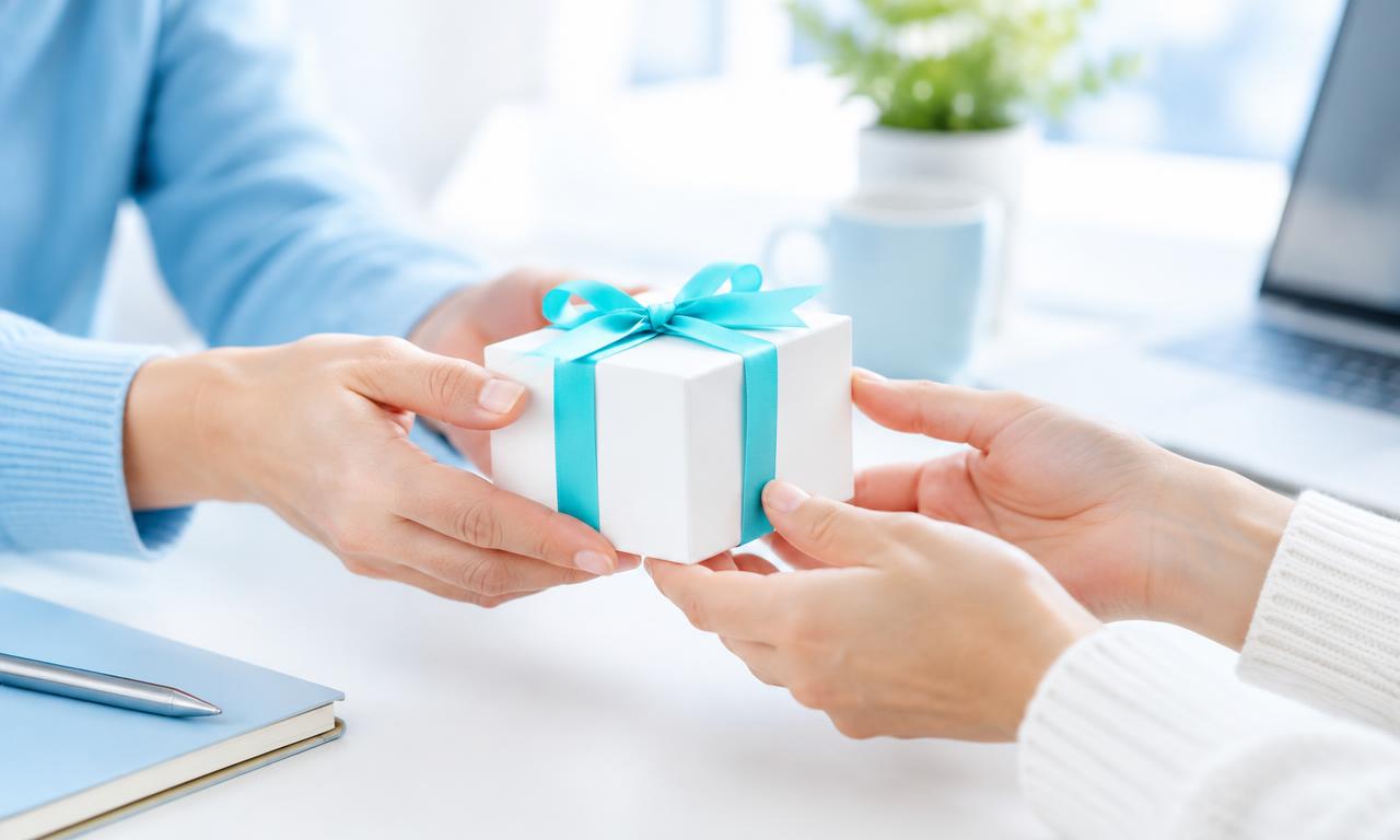 A gift box with a turquoise ribbon being shared